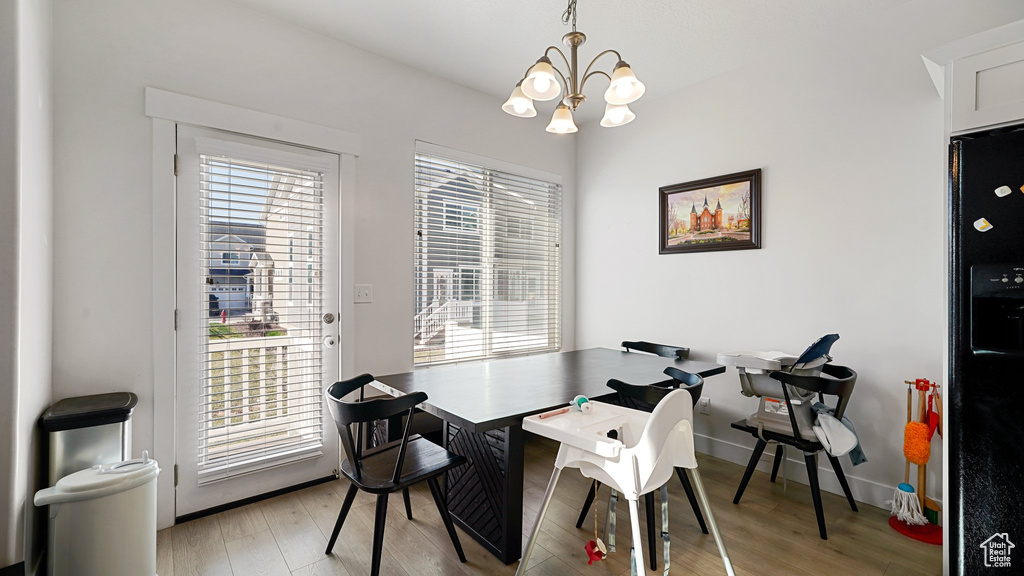 Dining room with baseboards, light wood finished floors, and a notable chandelier