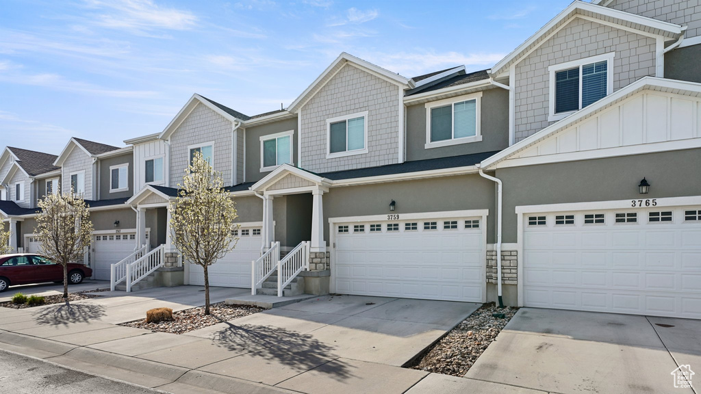 View of property with a residential view, stucco siding, driveway, board and batten siding, and an attached garage