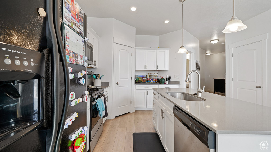 Kitchen with light wood-style flooring, white cabinetry, appliances with stainless steel finishes, a sink, and hanging light fixtures