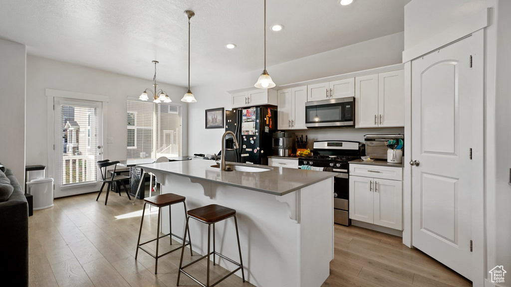 Kitchen with a chandelier, light wood-style floors, a breakfast bar, and stainless steel appliances