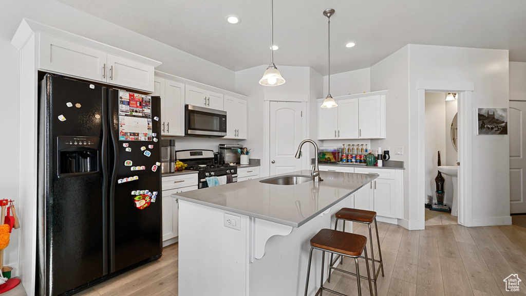 Kitchen featuring light wood-style floors, a sink, white cabinets, and stainless steel appliances