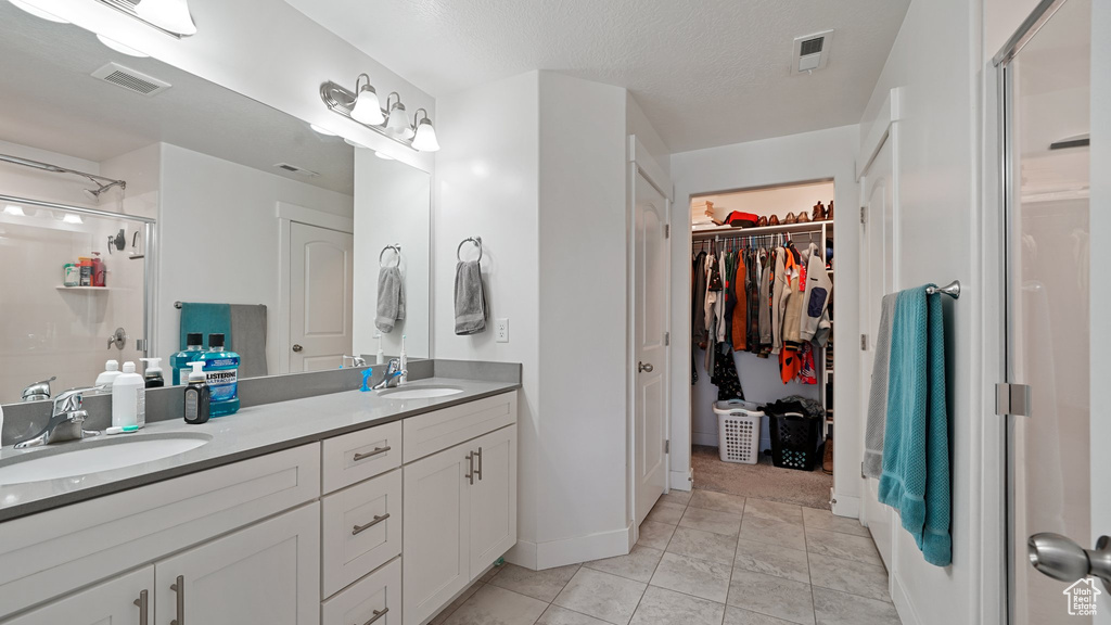 Bathroom featuring a sink, visible vents, a shower stall, and double vanity