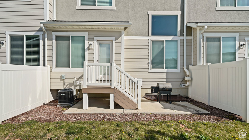 View of exterior entry with a patio area, fence, central AC unit, and stucco siding