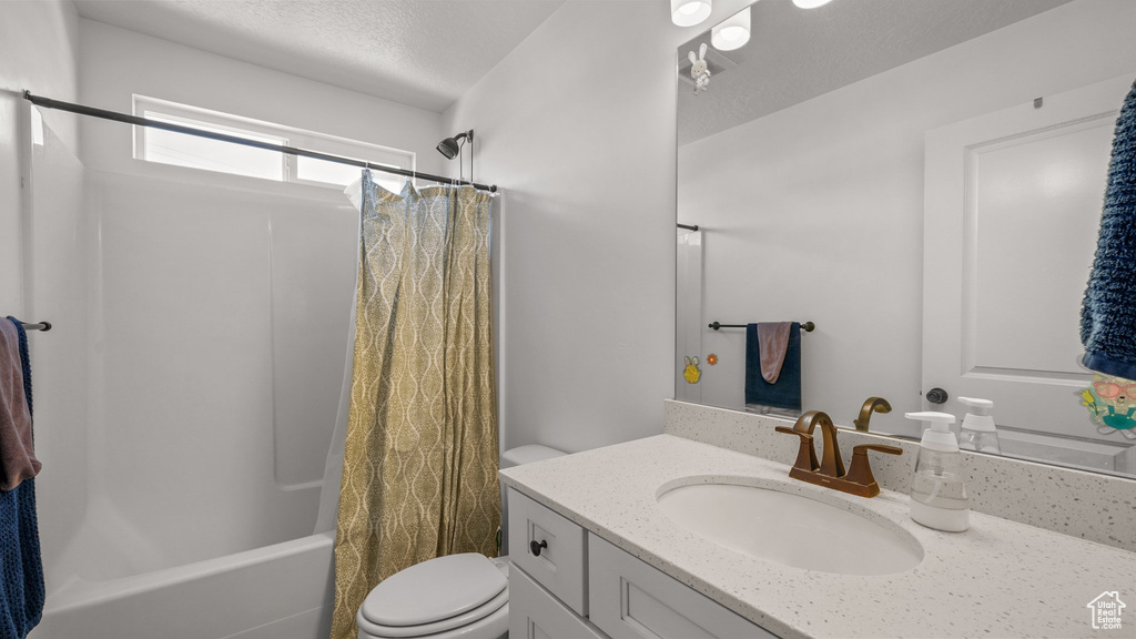 Bathroom with shower / tub combo, toilet, vanity, and a textured ceiling