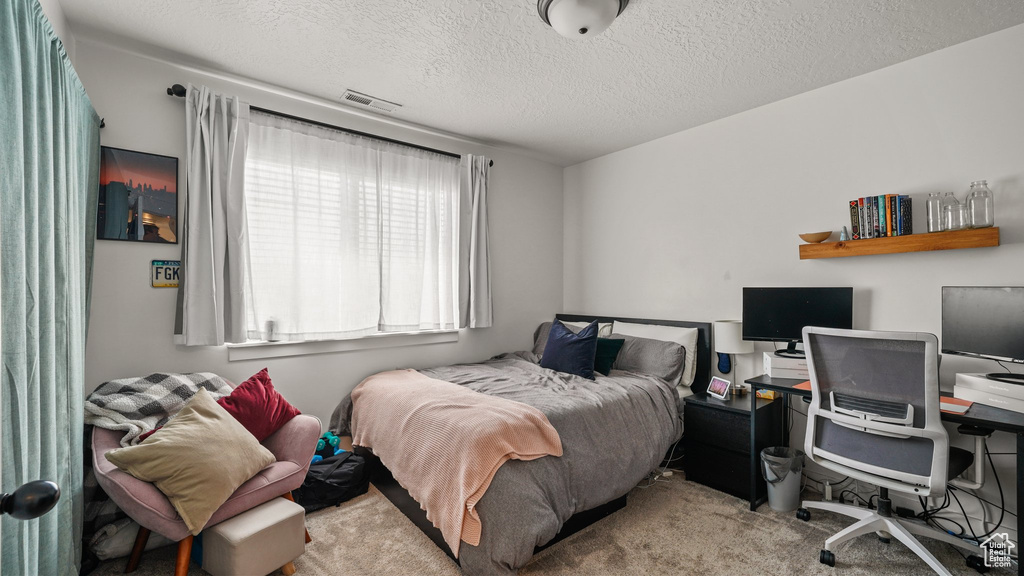 Carpeted bedroom with visible vents and a textured ceiling
