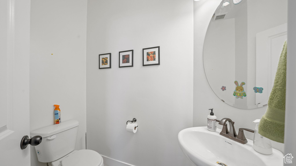 Bathroom featuring toilet, a sink, and visible vents