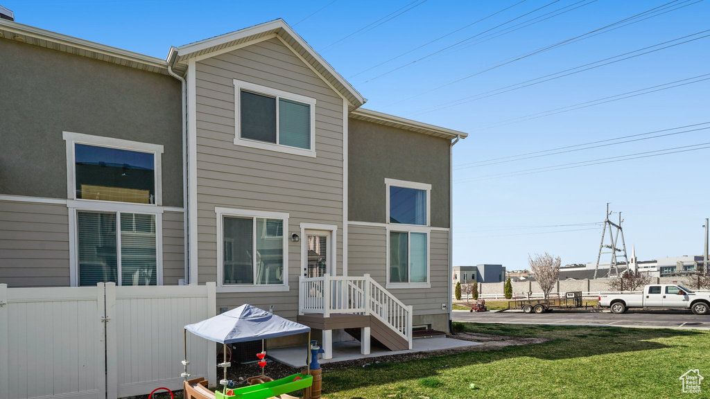 Back of house featuring a yard, fence, and stucco siding