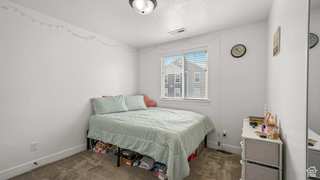 Bedroom with visible vents, baseboards, carpet, and a textured ceiling
