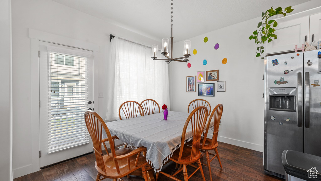 Dining space with dark wood-style flooring, a notable chandelier, and baseboards