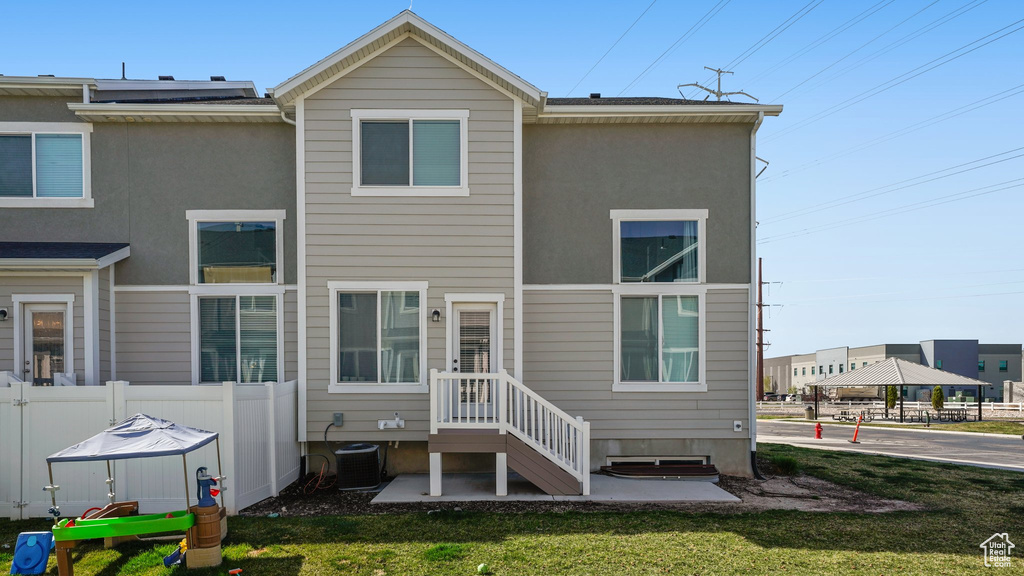 Back of house featuring central air condition unit, stucco siding, fence, and a lawn