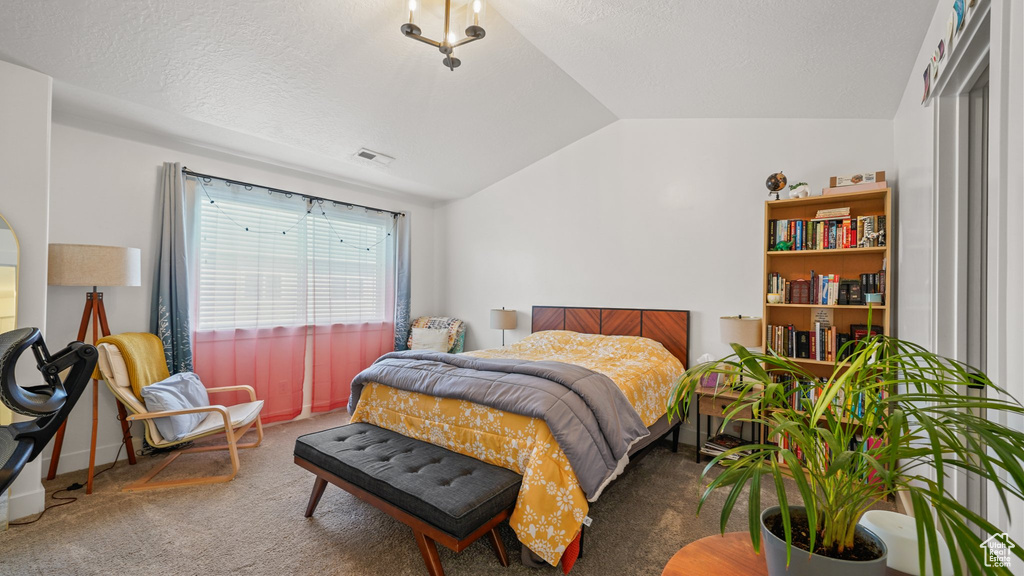 Carpeted bedroom featuring a textured ceiling, visible vents, and lofted ceiling