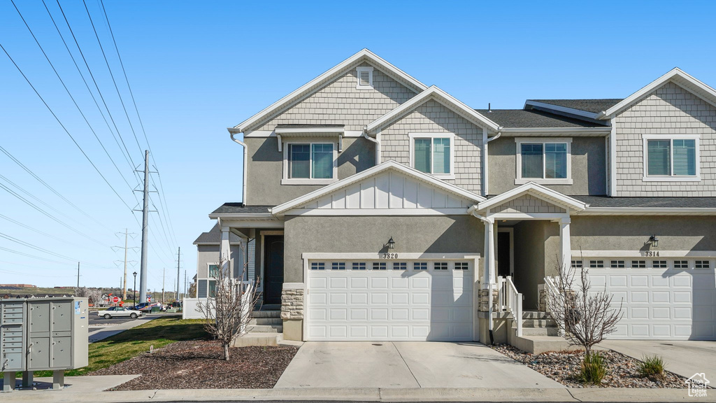 View of front of property featuring driveway, stucco siding, stone siding, and a garage