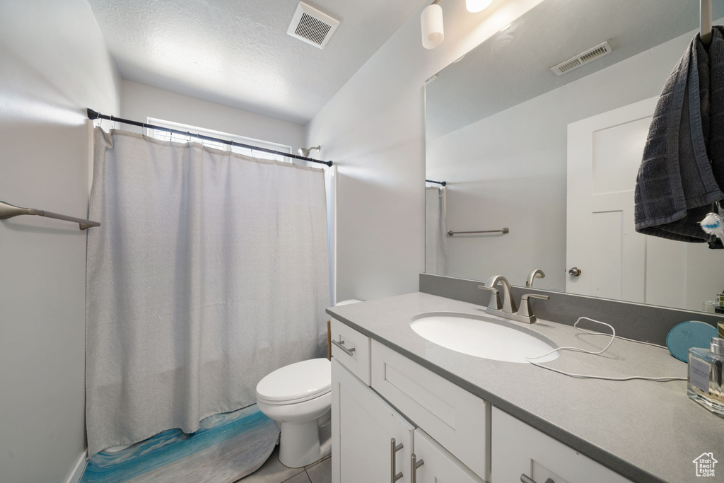 Full bath with visible vents, toilet, vanity, and a shower with curtain