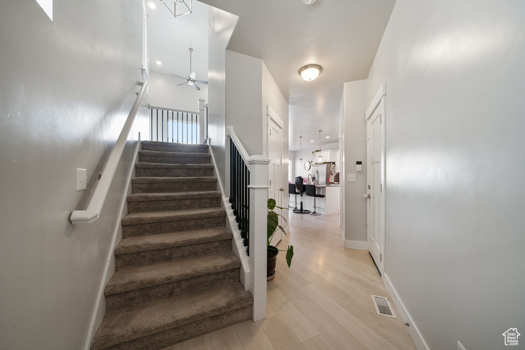 Staircase featuring visible vents, baseboards, a ceiling fan, and wood finished floors