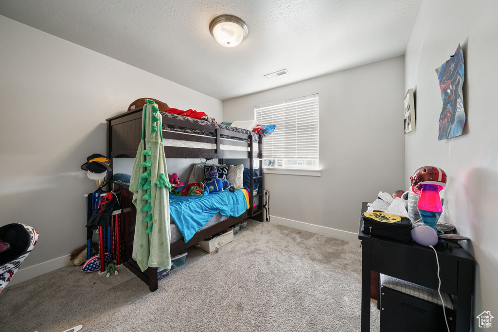 Bedroom featuring a textured ceiling, carpet flooring, baseboards, and visible vents