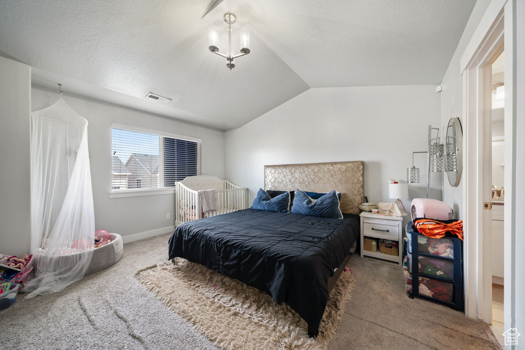 Carpeted bedroom with baseboards, vaulted ceiling, and visible vents