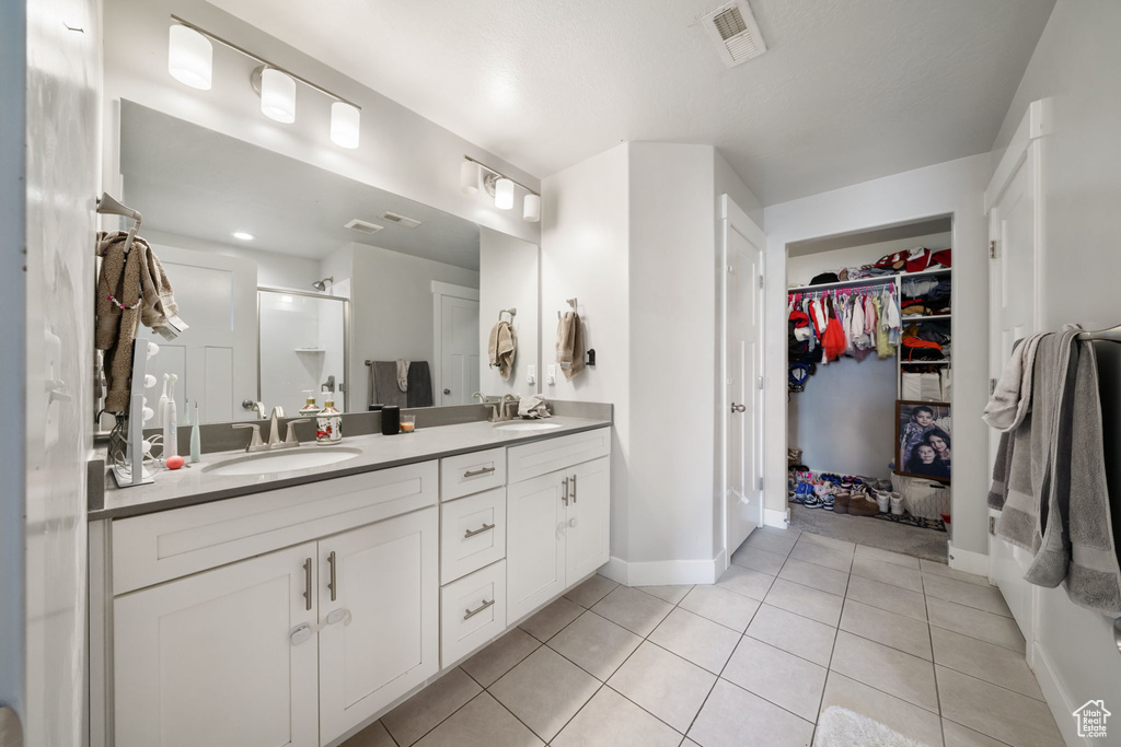 Full bathroom with a shower stall, tile patterned flooring, a sink, a walk in closet, and double vanity