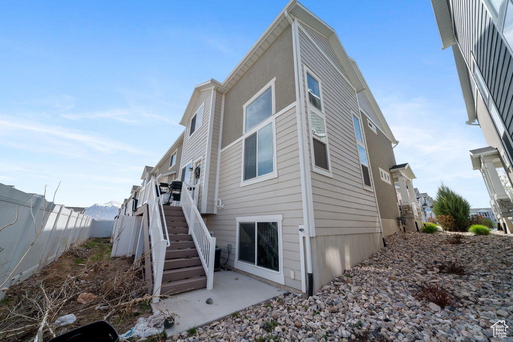 Rear view of property featuring a patio, a fenced backyard, and stairs