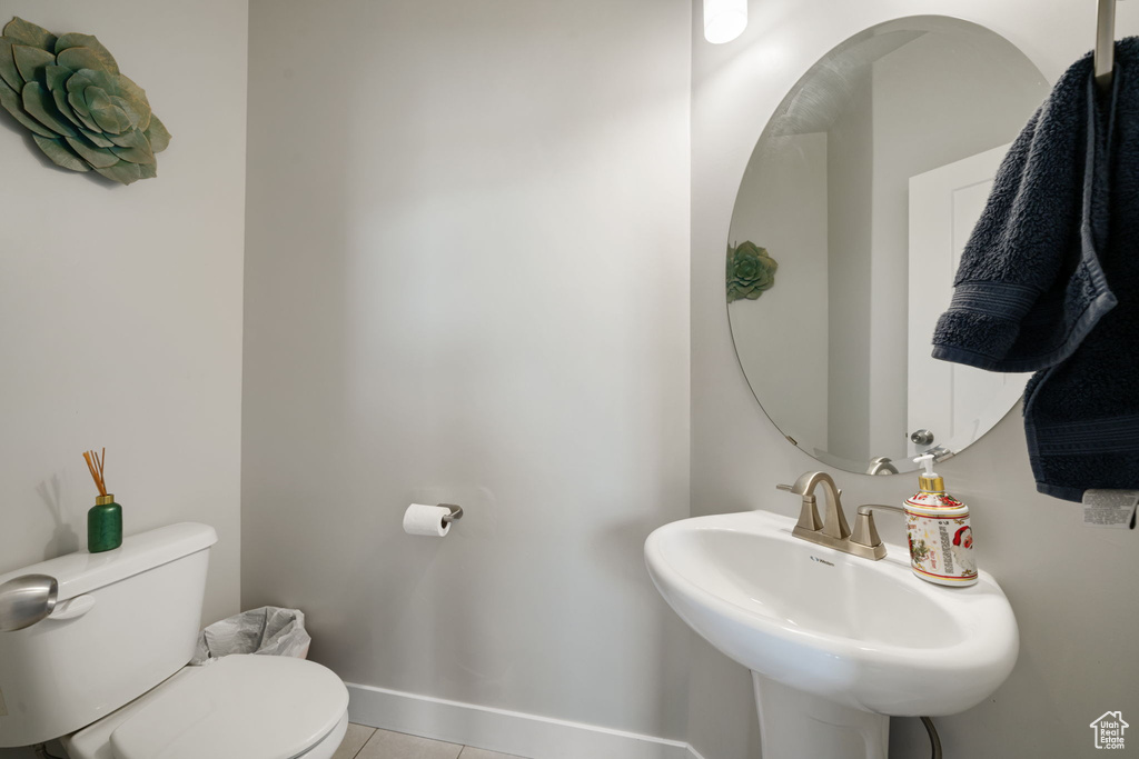 Half bath featuring toilet, tile patterned floors, a sink, and baseboards