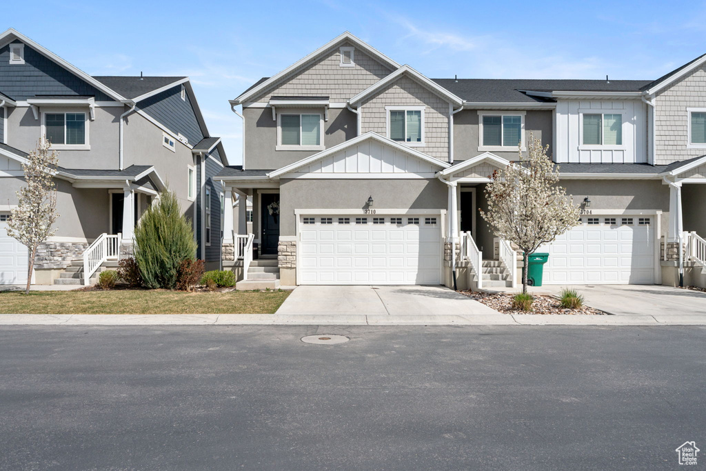 View of front of property featuring concrete driveway, stucco siding, board and batten siding, stone siding, and a garage
