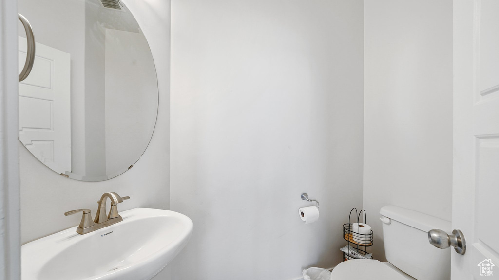 Bathroom with toilet, a sink, and visible vents