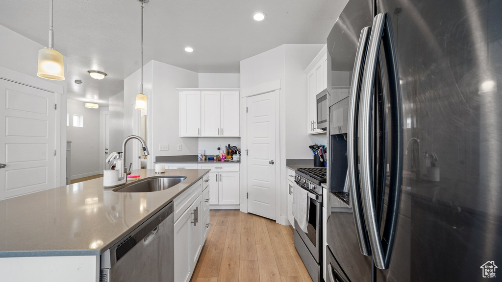Kitchen featuring white cabinets, light wood-style flooring, a sink, and appliances with stainless steel finishes