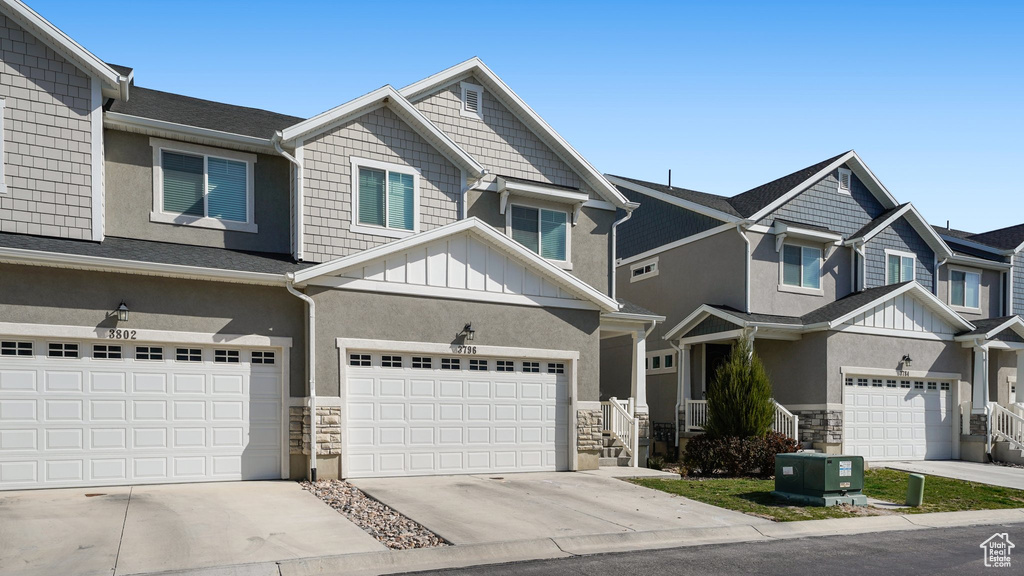 View of front of house featuring stucco siding, driveway, stone siding, board and batten siding, and an attached garage