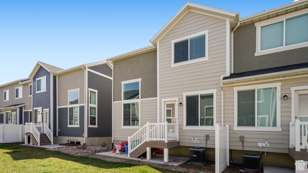 Back of property featuring a yard, central air condition unit, fence, and stucco siding