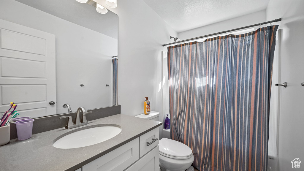 Bathroom with toilet, vanity, and shower / tub combo with curtain