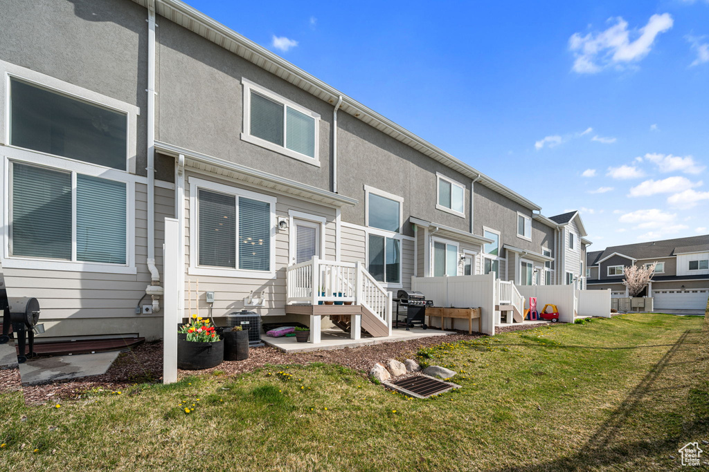 Rear view of house with central AC, stucco siding, a residential view, and a lawn