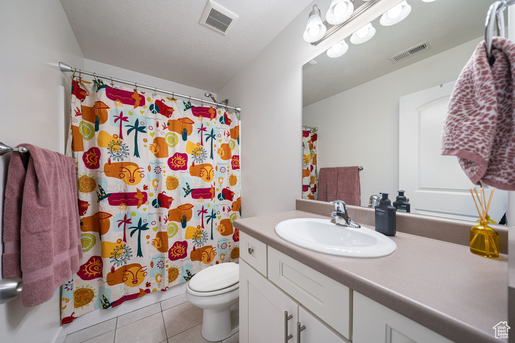 Bathroom with tile patterned flooring, vanity, visible vents, and toilet