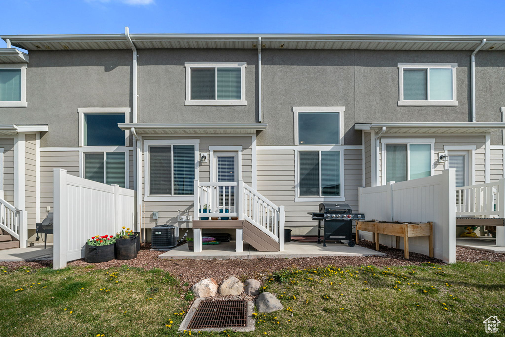 Rear view of property with central AC unit, a patio area, stucco siding, and fence