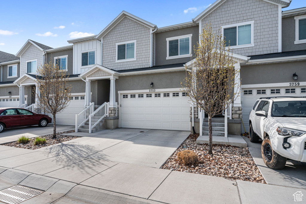 View of property with a garage, stucco siding, and concrete driveway