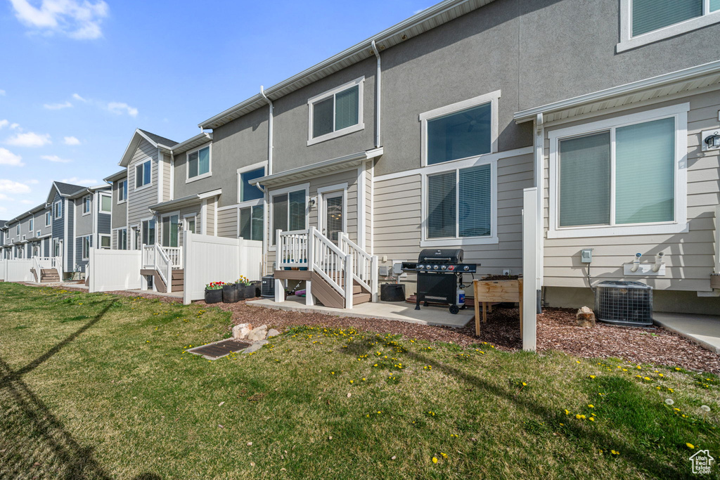 Rear view of house featuring a residential view, a patio, central air condition unit, stucco siding, and a lawn