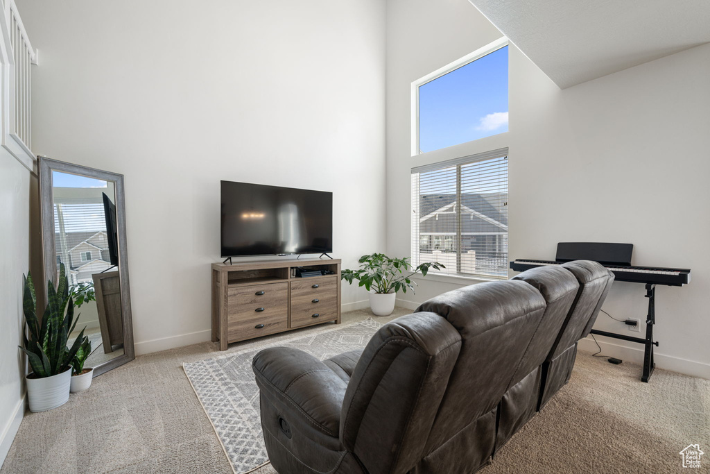 Carpeted living room with a towering ceiling and baseboards