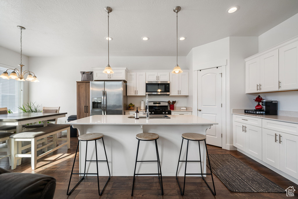 Kitchen with a breakfast bar, a sink, white cabinetry, and stainless steel appliances