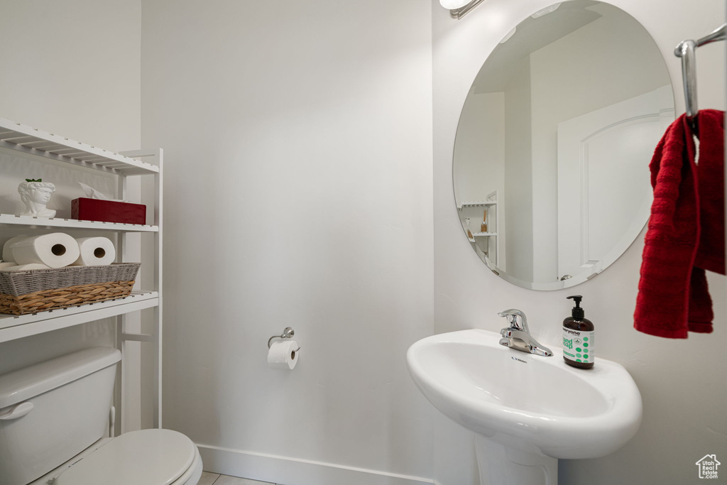 Half bathroom featuring tile patterned floors, baseboards, a sink, and toilet