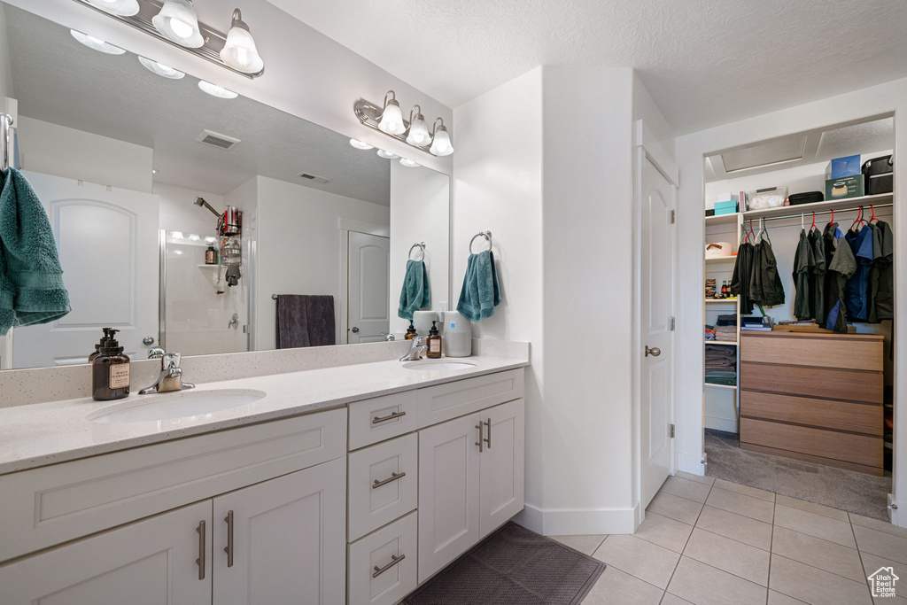 Bathroom with tile patterned floors, double vanity, a sink, and visible vents
