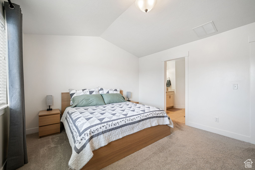Bedroom featuring carpet, ensuite bath, visible vents, lofted ceiling, and baseboards