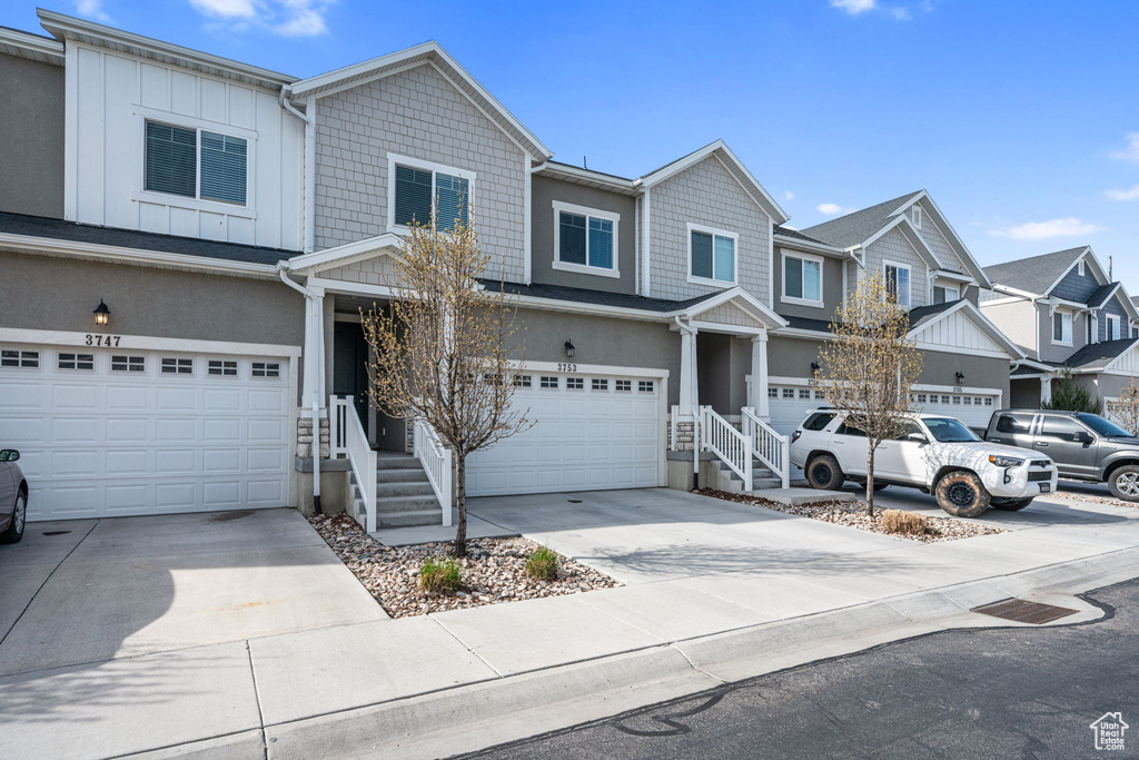 Multi unit property featuring a garage, board and batten siding, stucco siding, a residential view, and driveway