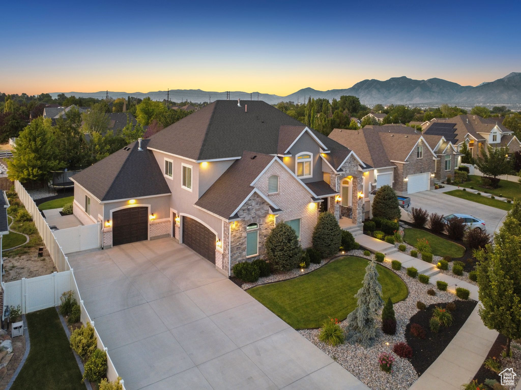 Traditional-style home featuring stone siding, a garage, concrete driveway, and a mountain view