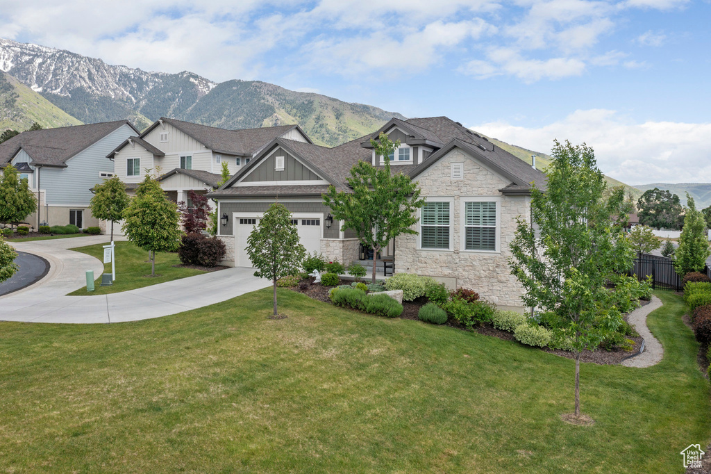 Craftsman-style house with stone siding, driveway, board and batten siding, a mountain view, and a garage