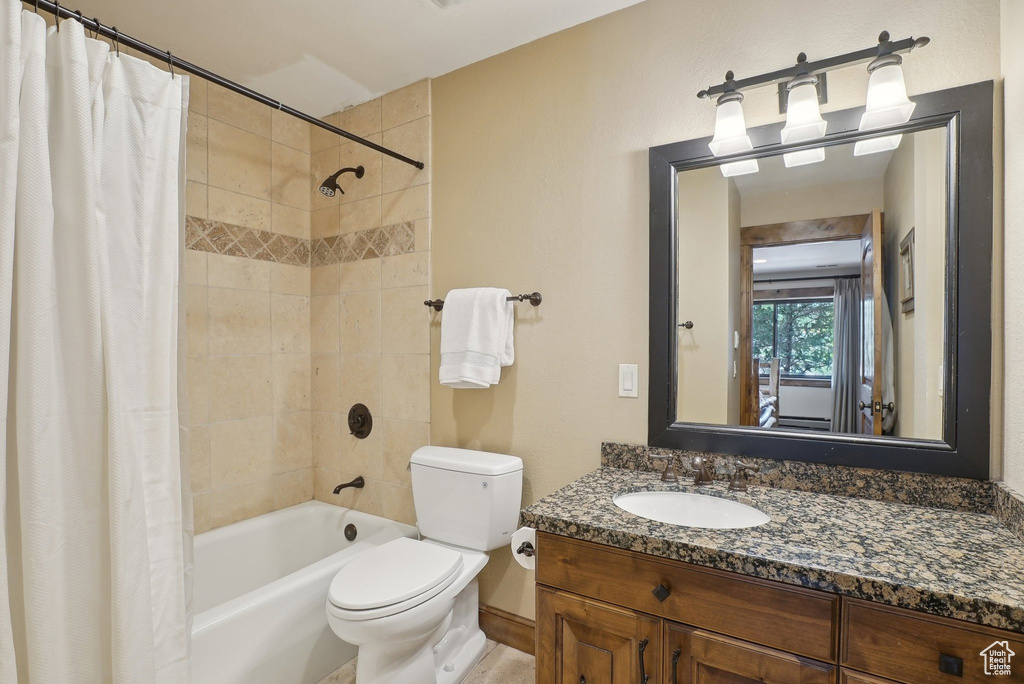 Bathroom with toilet, shower / bathtub combination with curtain, and vanity