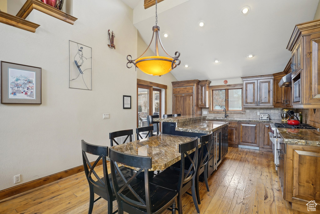 Kitchen with dark stone countertops, a center island, backsplash, appliances with stainless steel finishes, and light wood finished floors