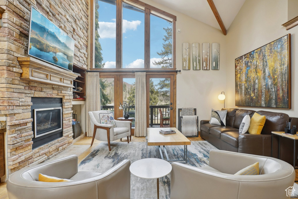 Living area with high vaulted ceiling, beam ceiling, and a stone fireplace