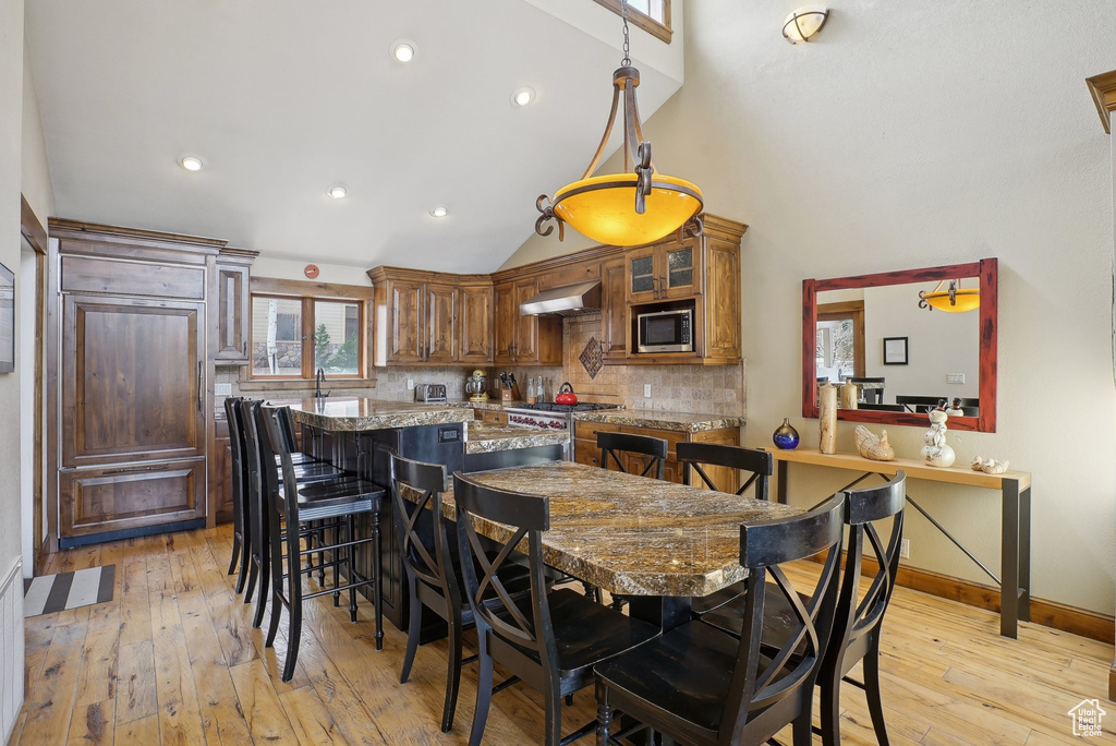 Dining area with high vaulted ceiling, recessed lighting, light wood-type flooring, and baseboards