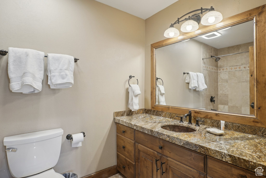 Bathroom featuring vanity, baseboards, toilet, tiled shower, and visible vents