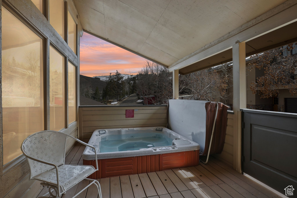 Deck at dusk featuring a covered hot tub