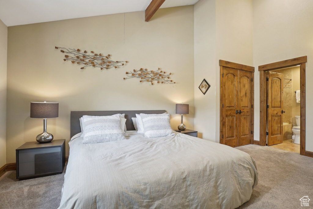 Bedroom with ensuite bathroom, baseboards, beamed ceiling, a towering ceiling, and carpet flooring