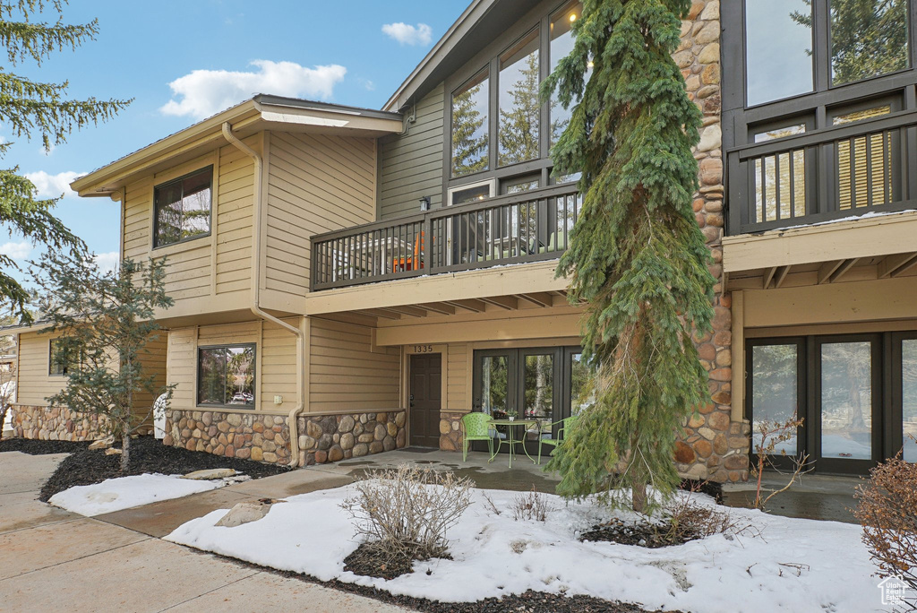 Exterior space featuring a balcony, french doors, and stone siding